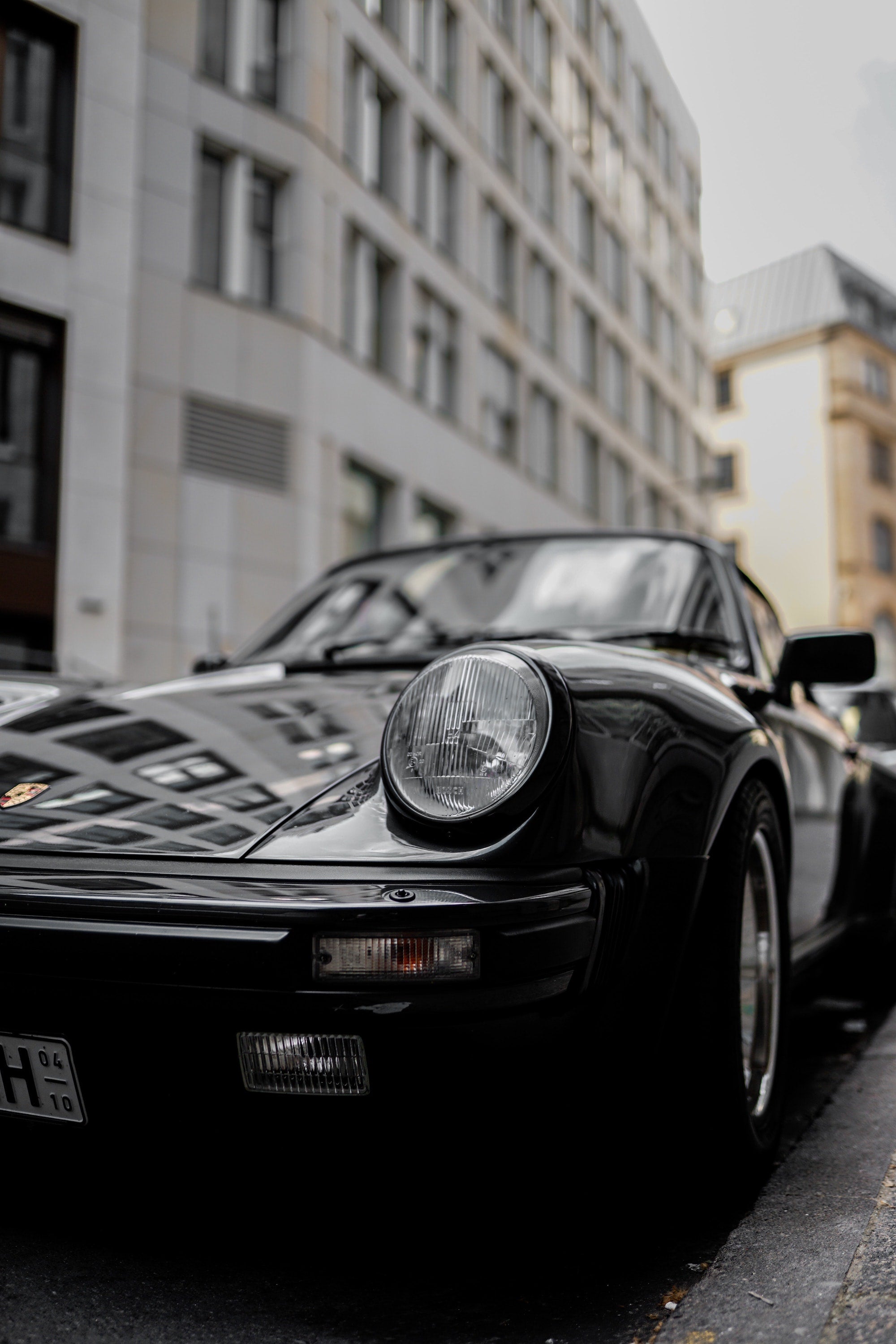 A classic Porsche close-up with city buildings in the background